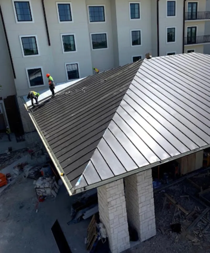 Crew installing standing seam metal roof panels on a commercial project in North Huntingdon